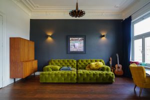 Immobilienfotografie in Hamburg – Altbau Wohnzimmer mit Samtsofa, dunklem Holzboden und Stuckdecke